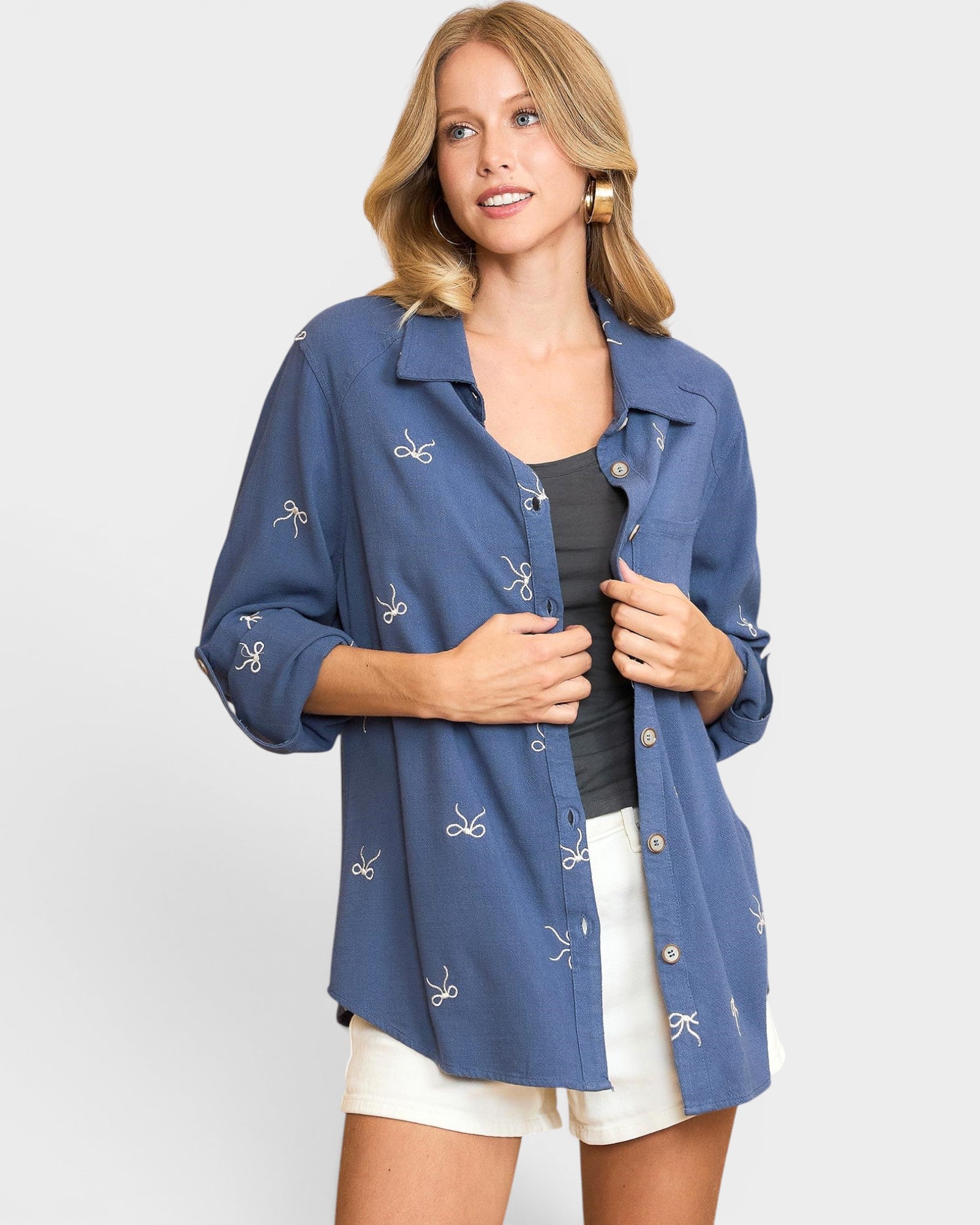 Woman wearing a blue shirt with white patterns on a plain background