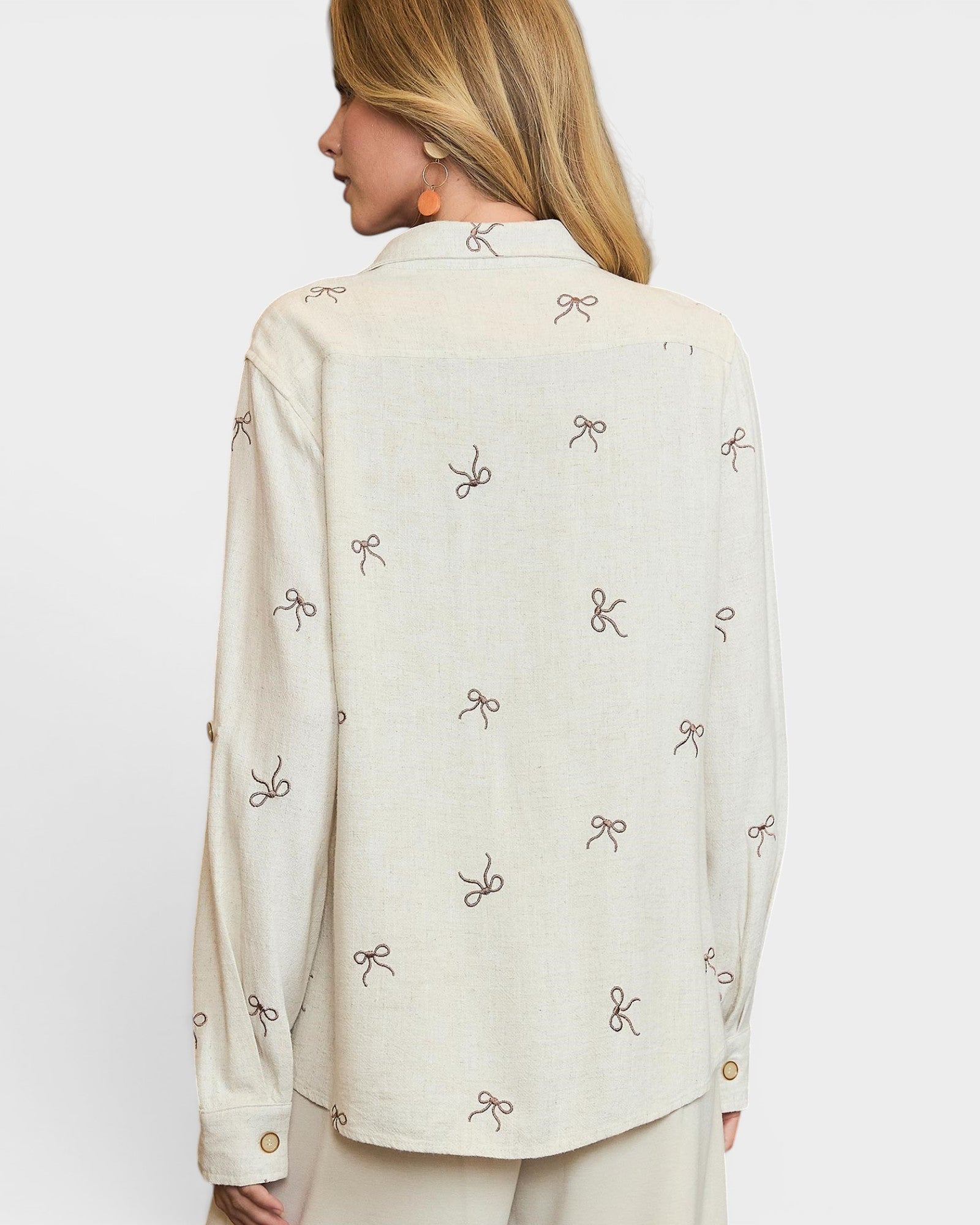 Woman wearing a cream-colored blouse with bow pattern on a white background