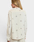 Woman wearing a cream-colored blouse with bow pattern on a white background