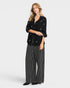 Woman wearing a black patterned top and striped pants on a white background