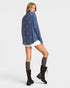 Woman wearing a blue patterned shirt, white shorts, and black boots on a white background