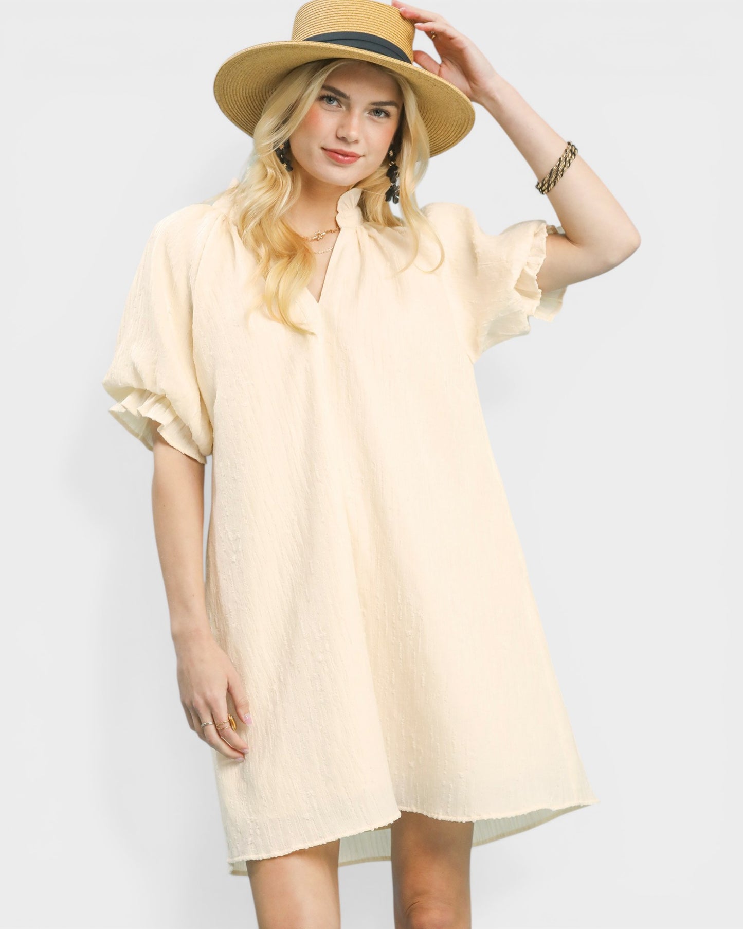 Woman wearing a light yellow dress and hat on a plain background