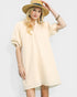 Woman wearing a light yellow dress and hat on a plain background