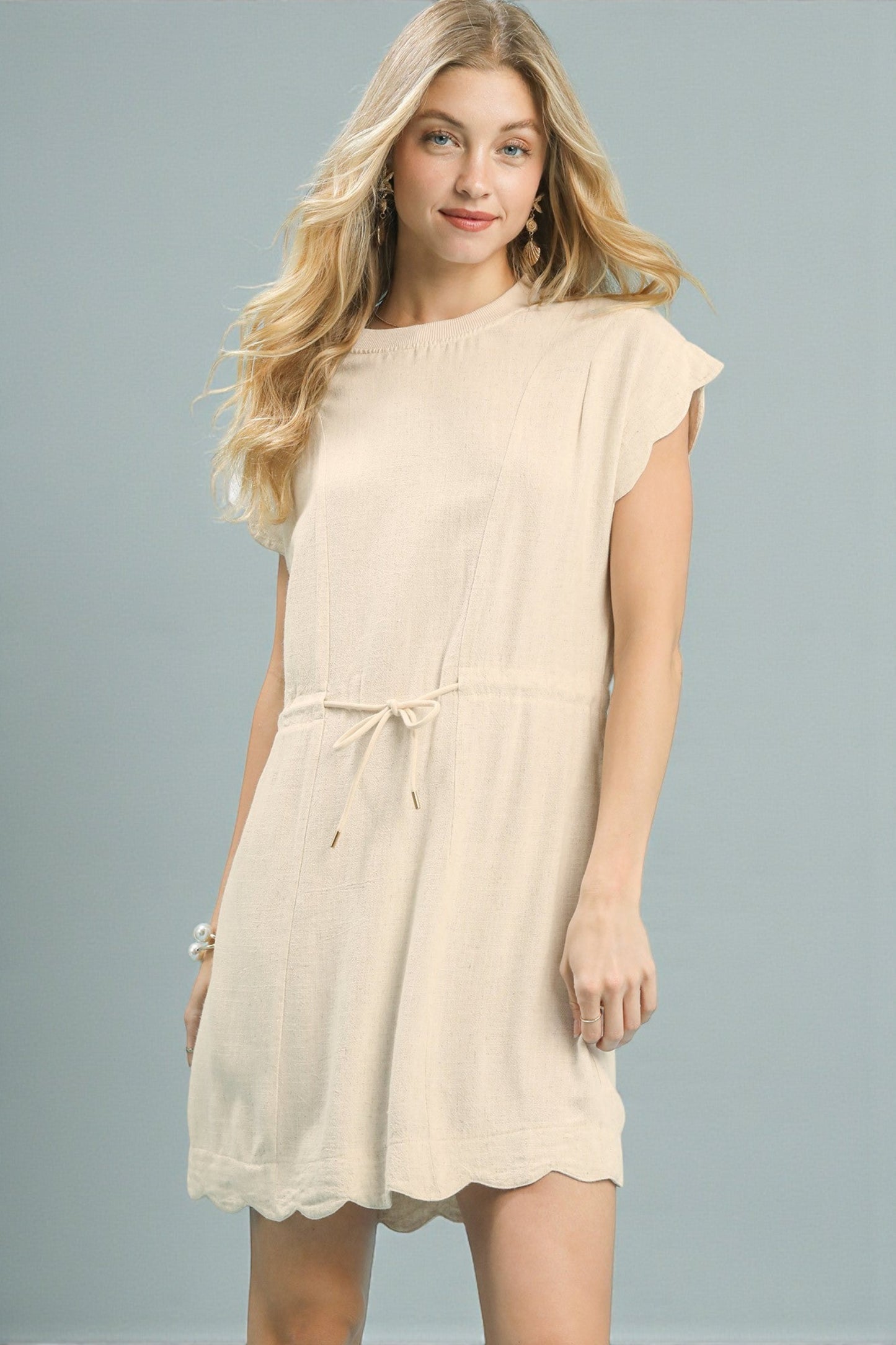 Woman wearing a beige dress against a gray background