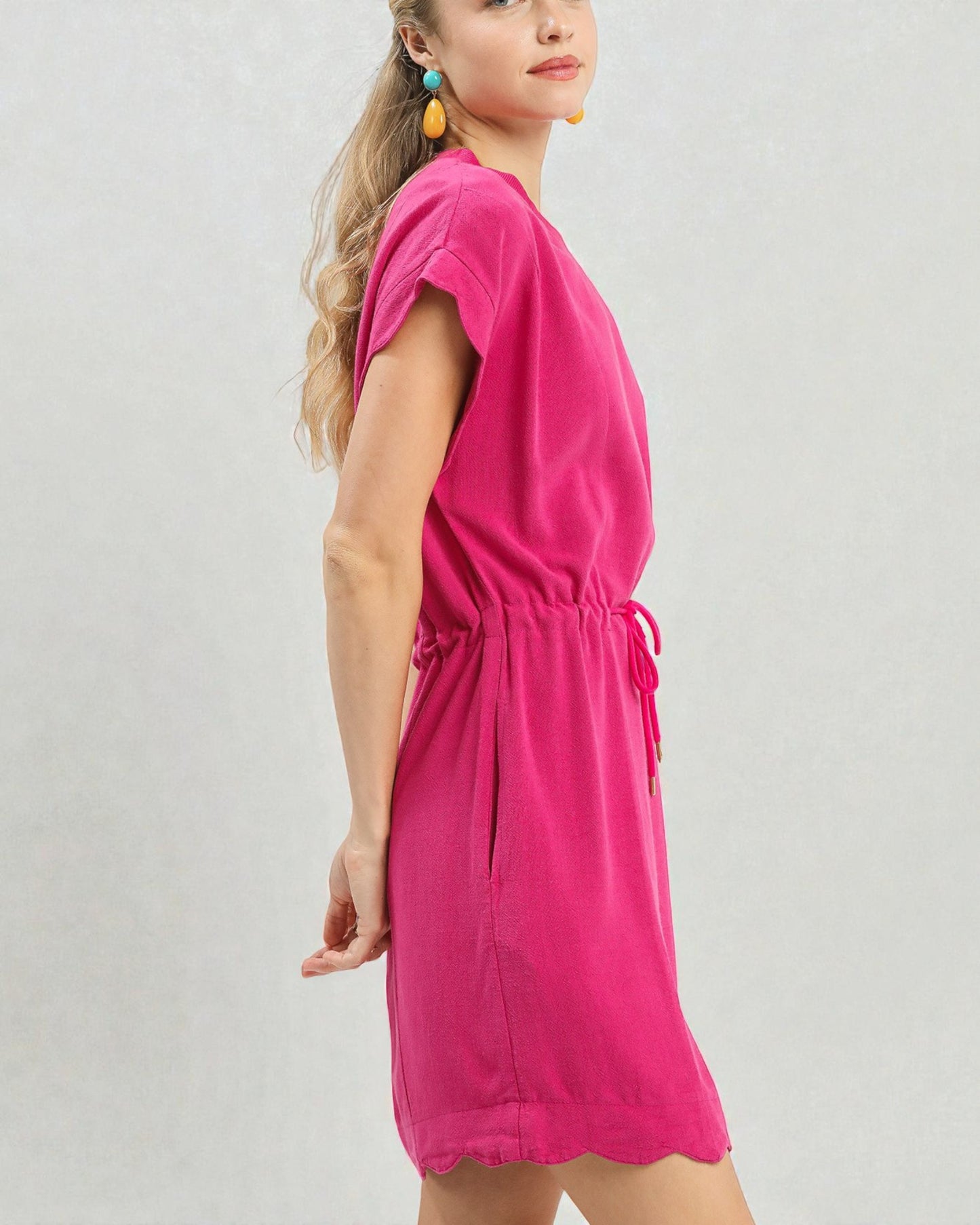 Woman wearing a bright pink dress on a plain background