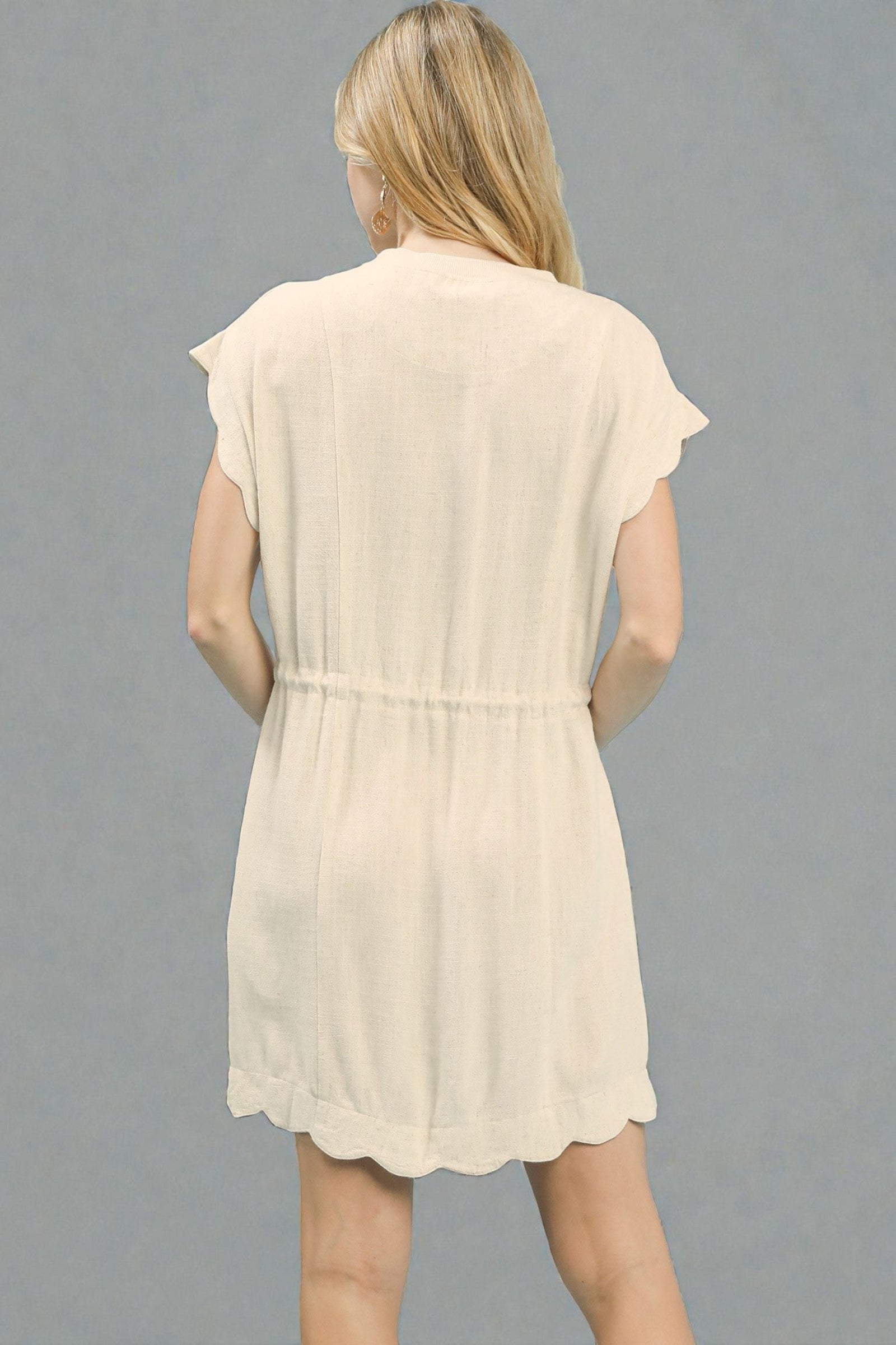 Beige sleeveless dress worn by a person on a gray background