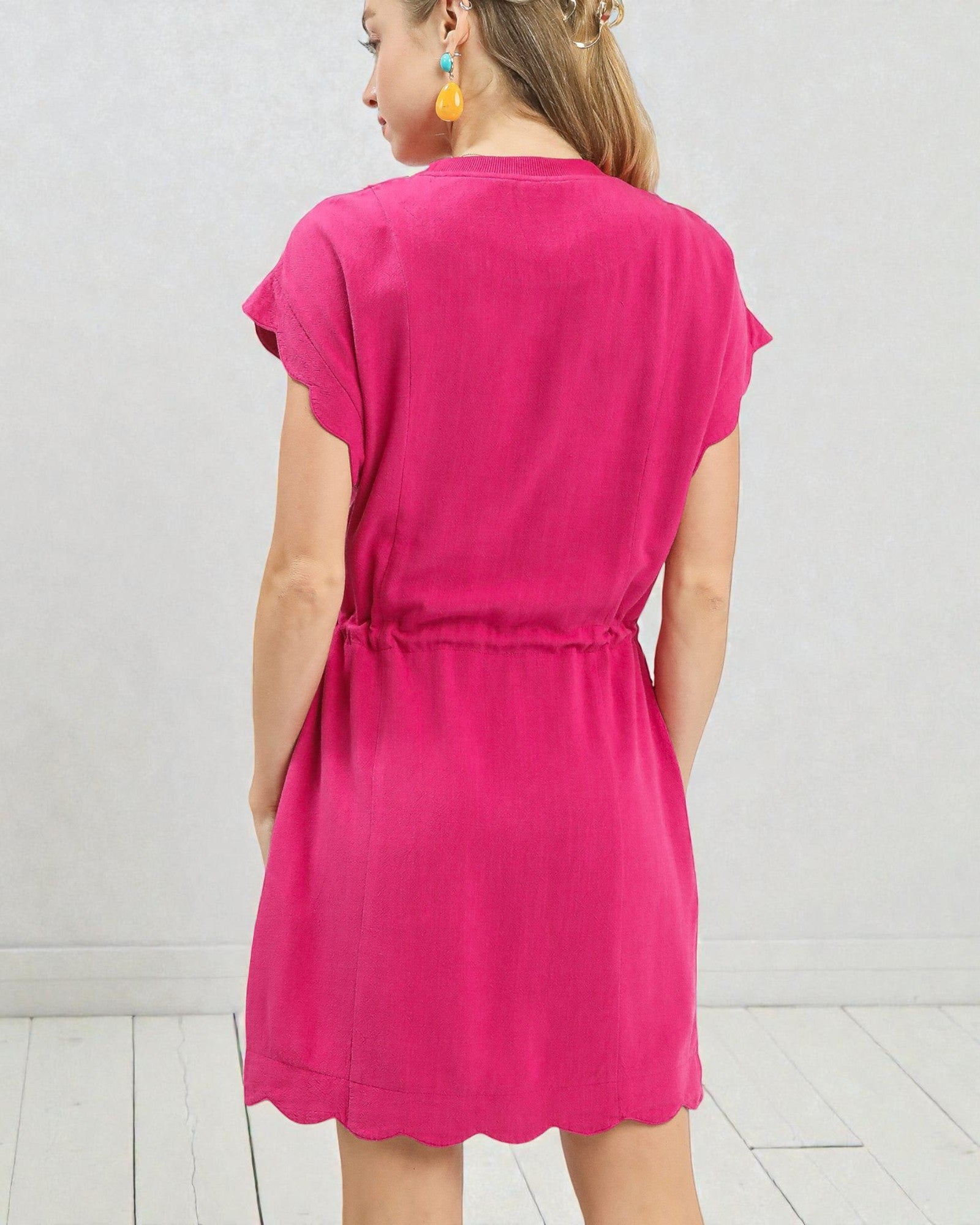 Person wearing a bright pink dress against a white background