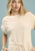 Woman wearing a beige dress against a light blue background