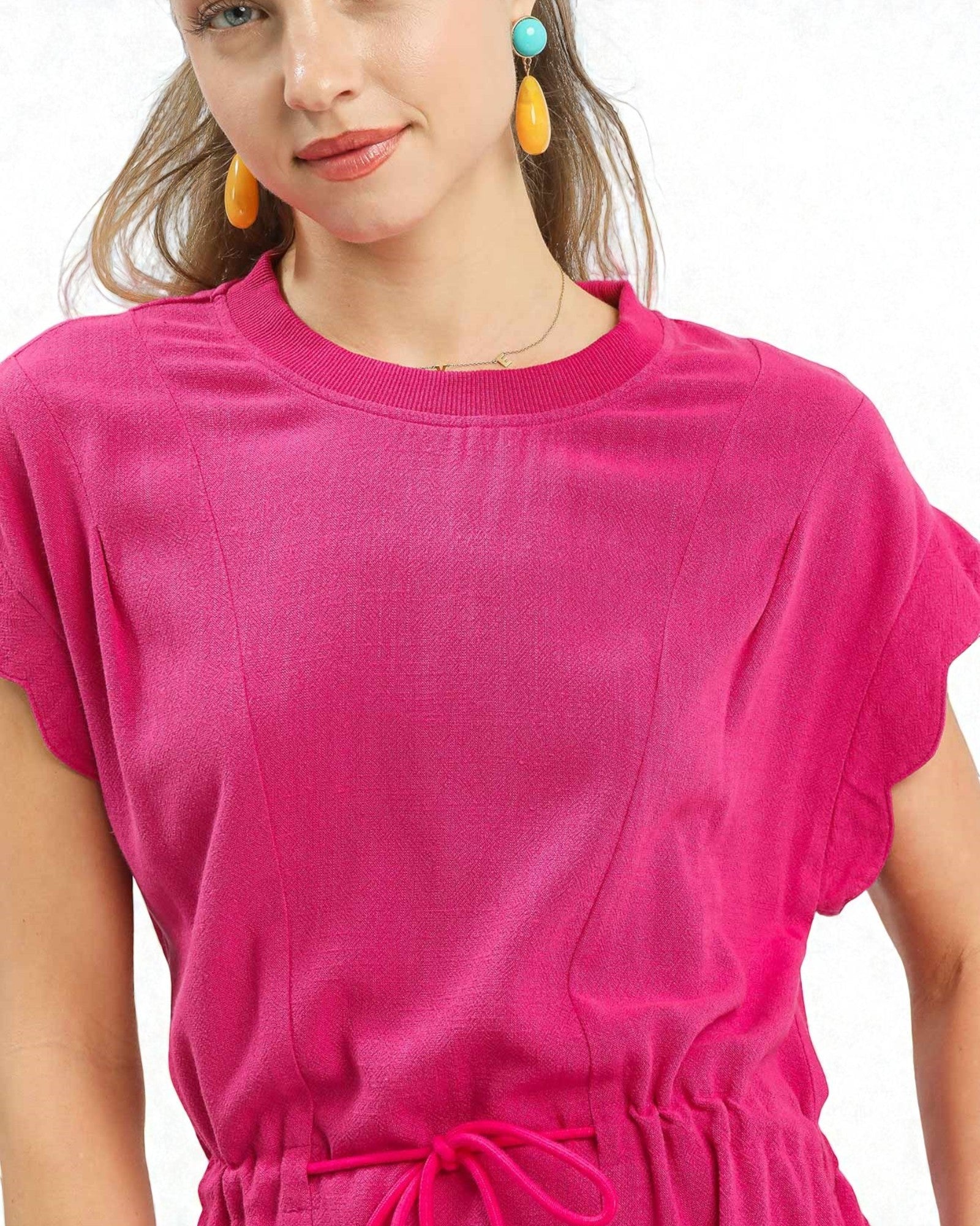 Woman wearing a bright pink dress with a plain background