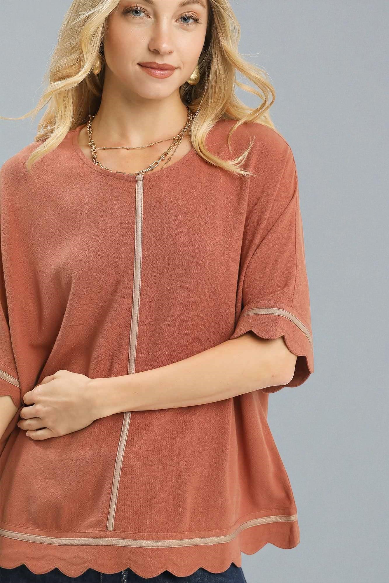 Woman wearing a rust-colored top with a plain background