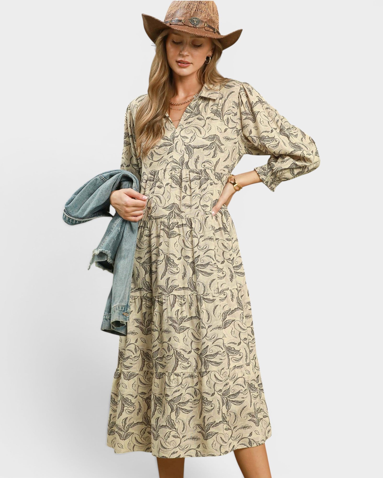 Woman wearing a patterned dress with a denim jacket on a white background