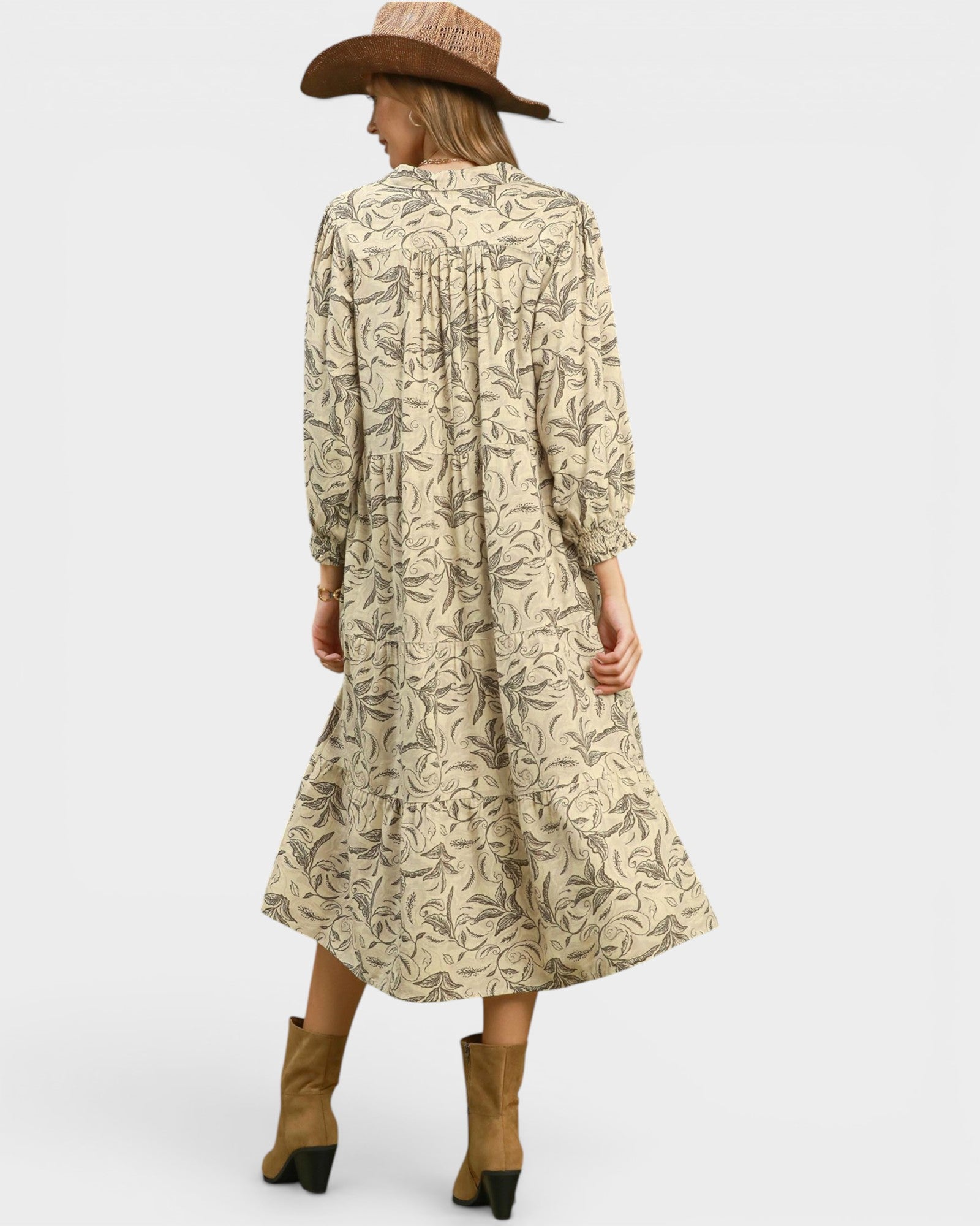 Woman wearing a patterned dress with long sleeves and a hat on a white background
