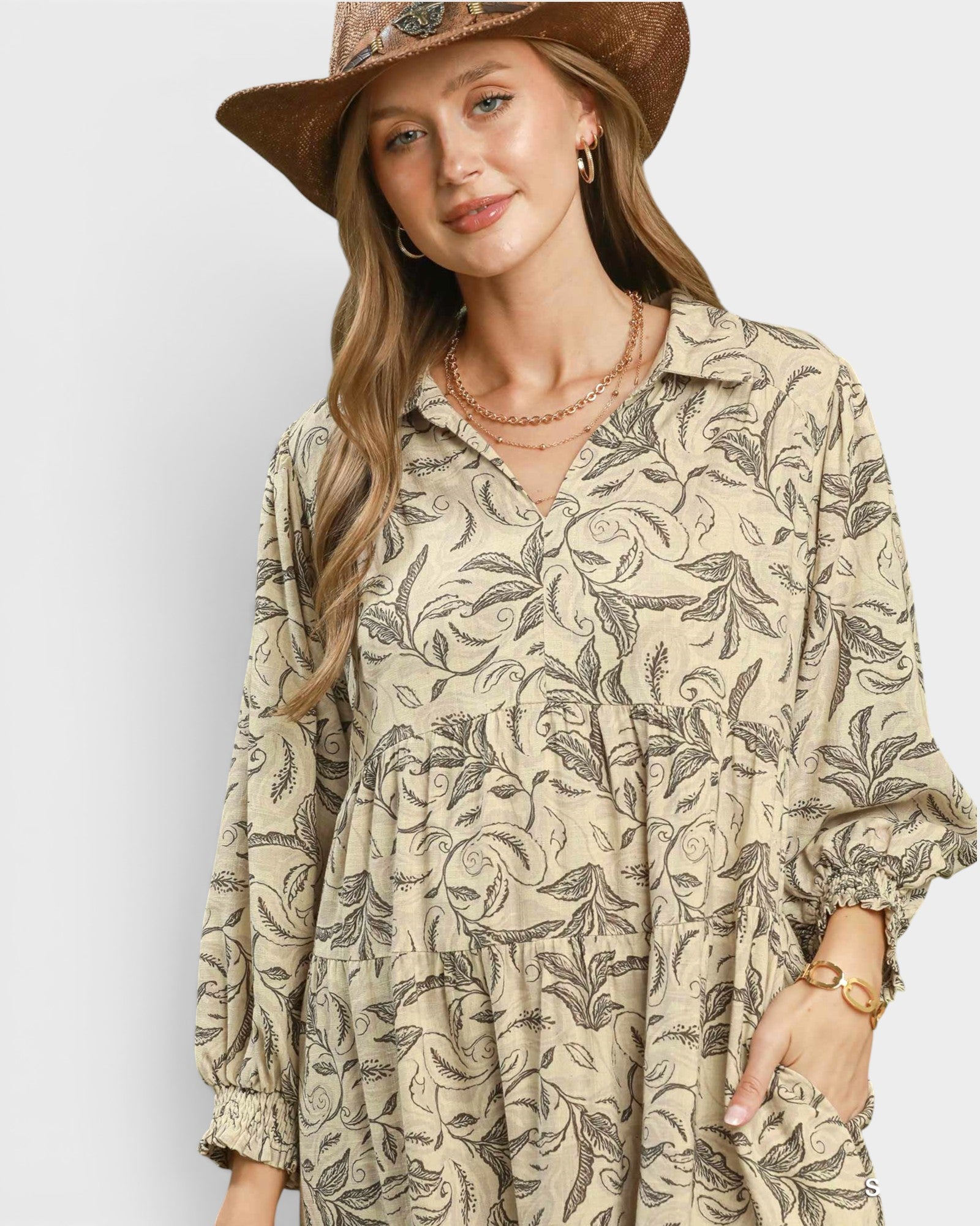 Woman wearing a patterned shirt and hat on a plain background