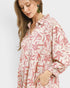 Woman wearing a red and white floral patterned dress on a light gray background