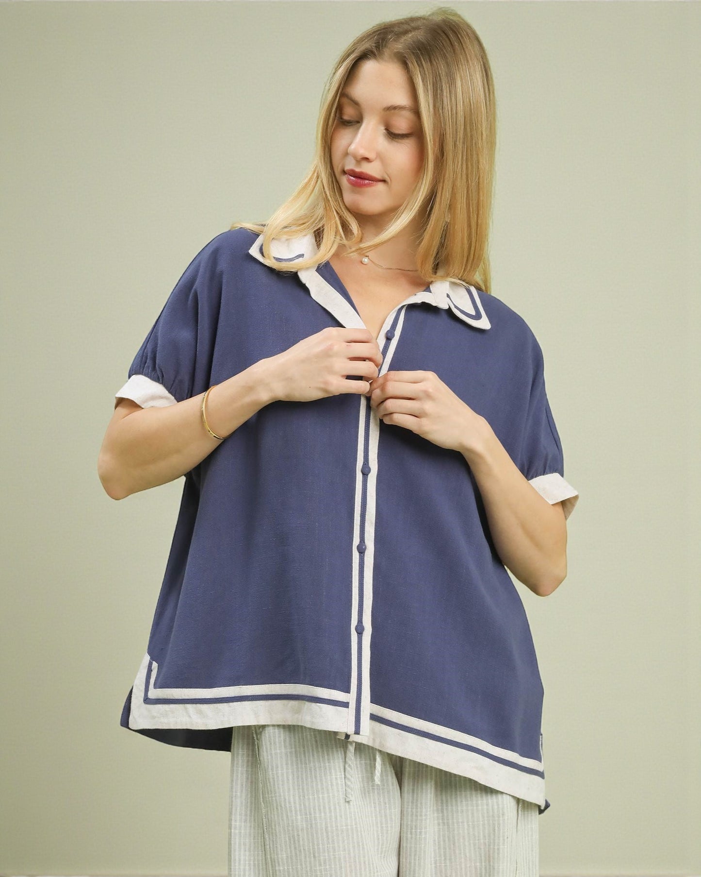 Woman wearing a blue and white top with a plain background