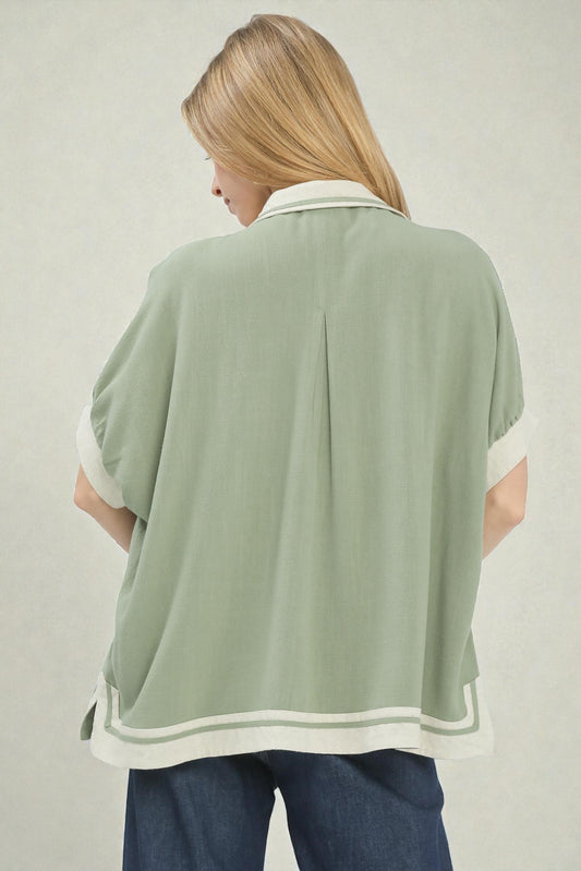 Woman wearing a green poncho with white trim on a plain background