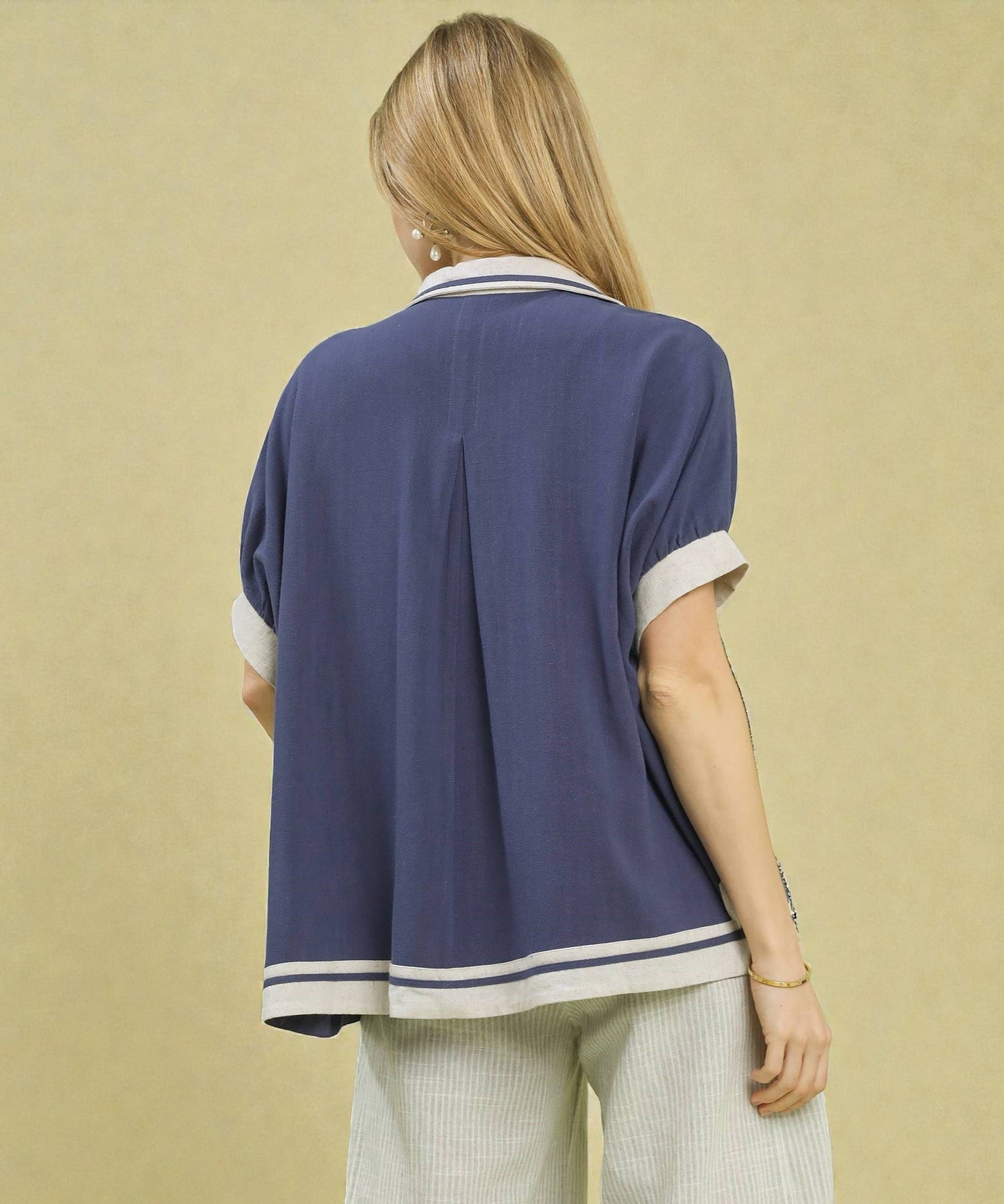 Person wearing a navy blue shirt with white trim on a beige background