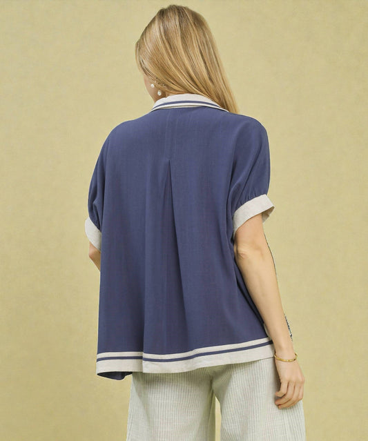 Person wearing a navy blue shirt with white trim on a beige background