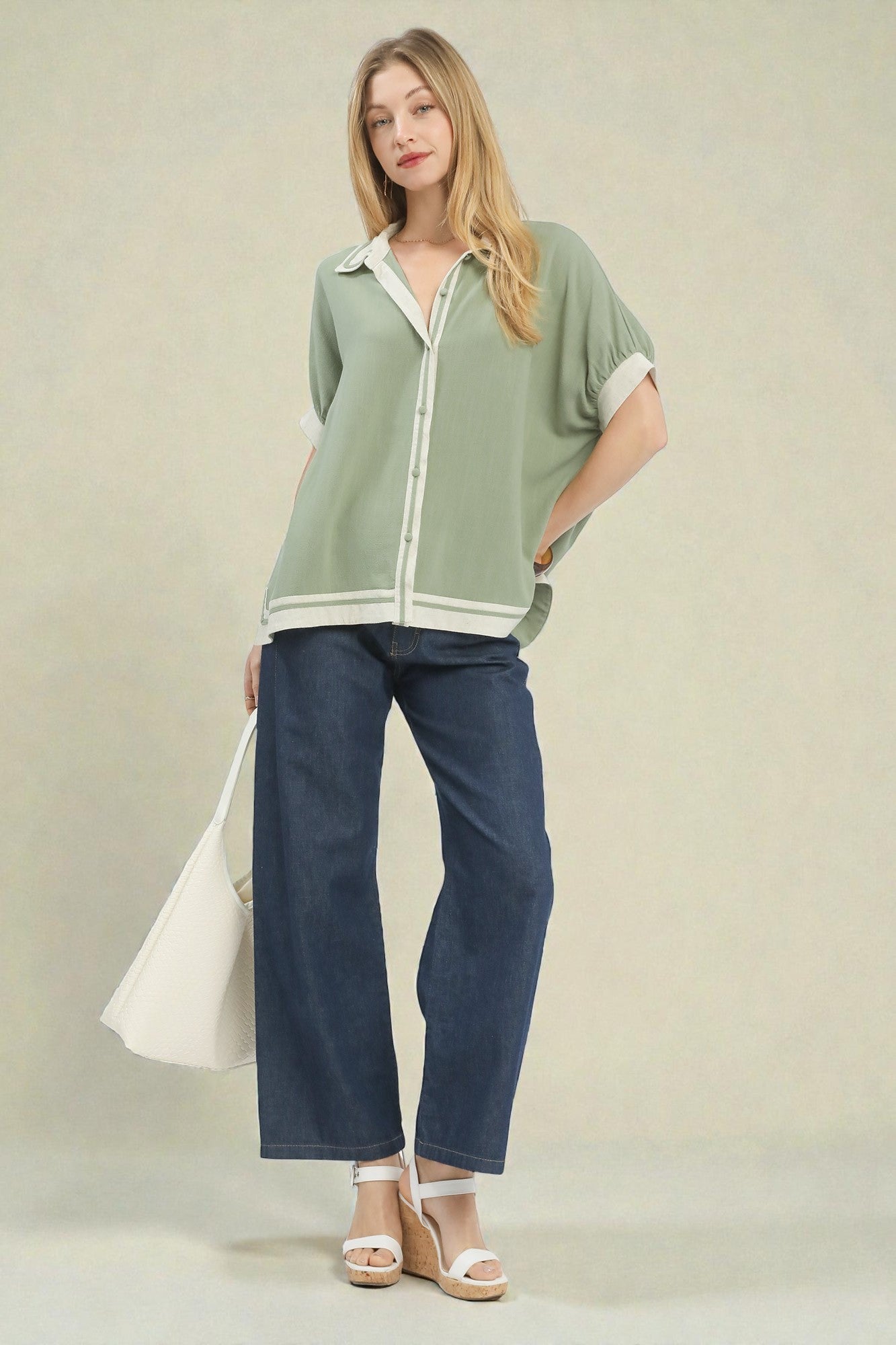 Woman wearing a green shirt and blue jeans against a plain background