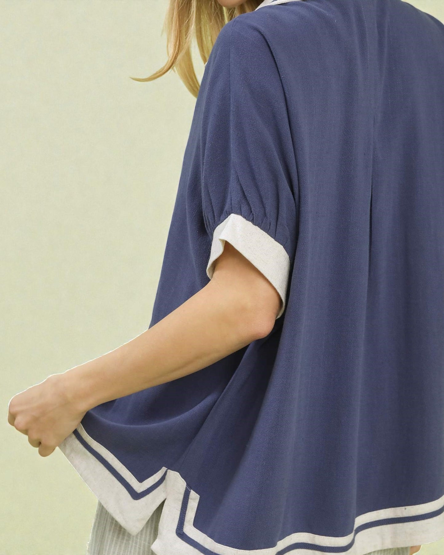 Person wearing a blue kimono-style garment with white trim on a light green background