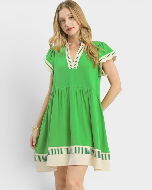 Woman wearing a green dress with white trim on a white background