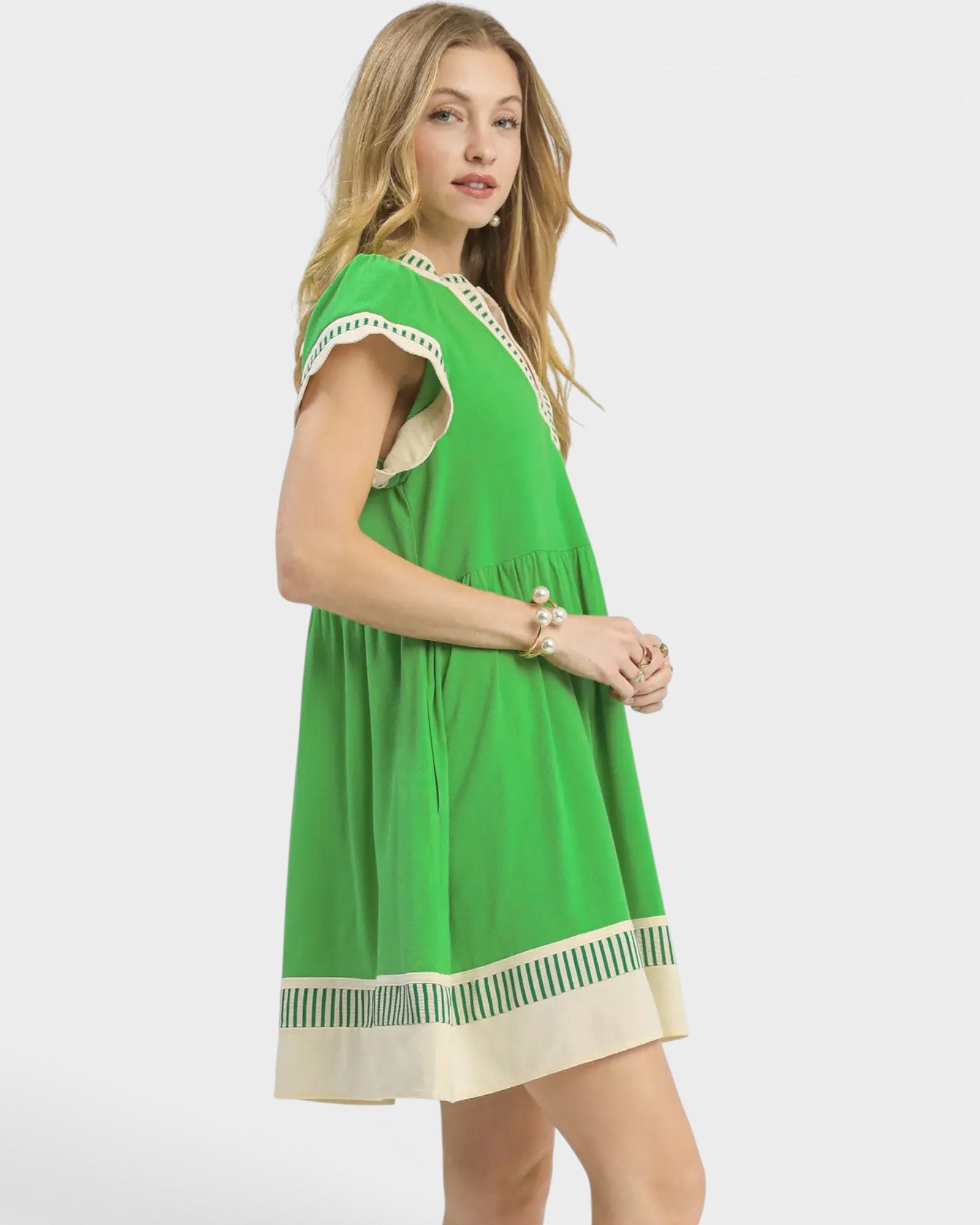 Woman wearing a green dress with beige accents on a white background