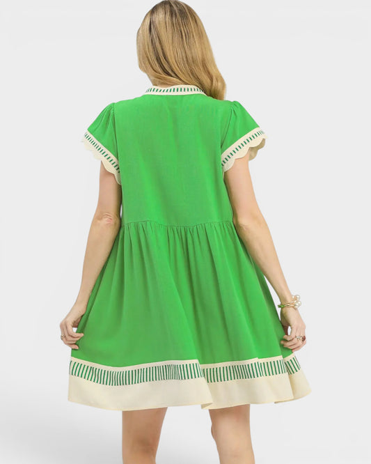 Green dress with white trim worn by a person on a white background