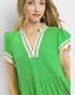 Woman wearing a green dress with white and green trim against a light gray background