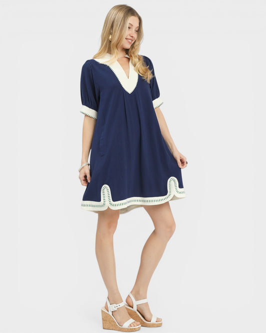 Woman wearing a navy dress with white trim on a white background