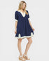 Woman wearing a navy dress with white trim on a white background