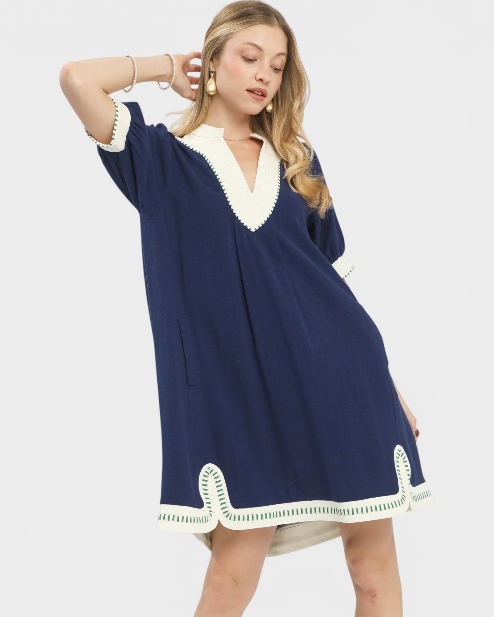 Woman wearing a navy dress with white trim on a white background
