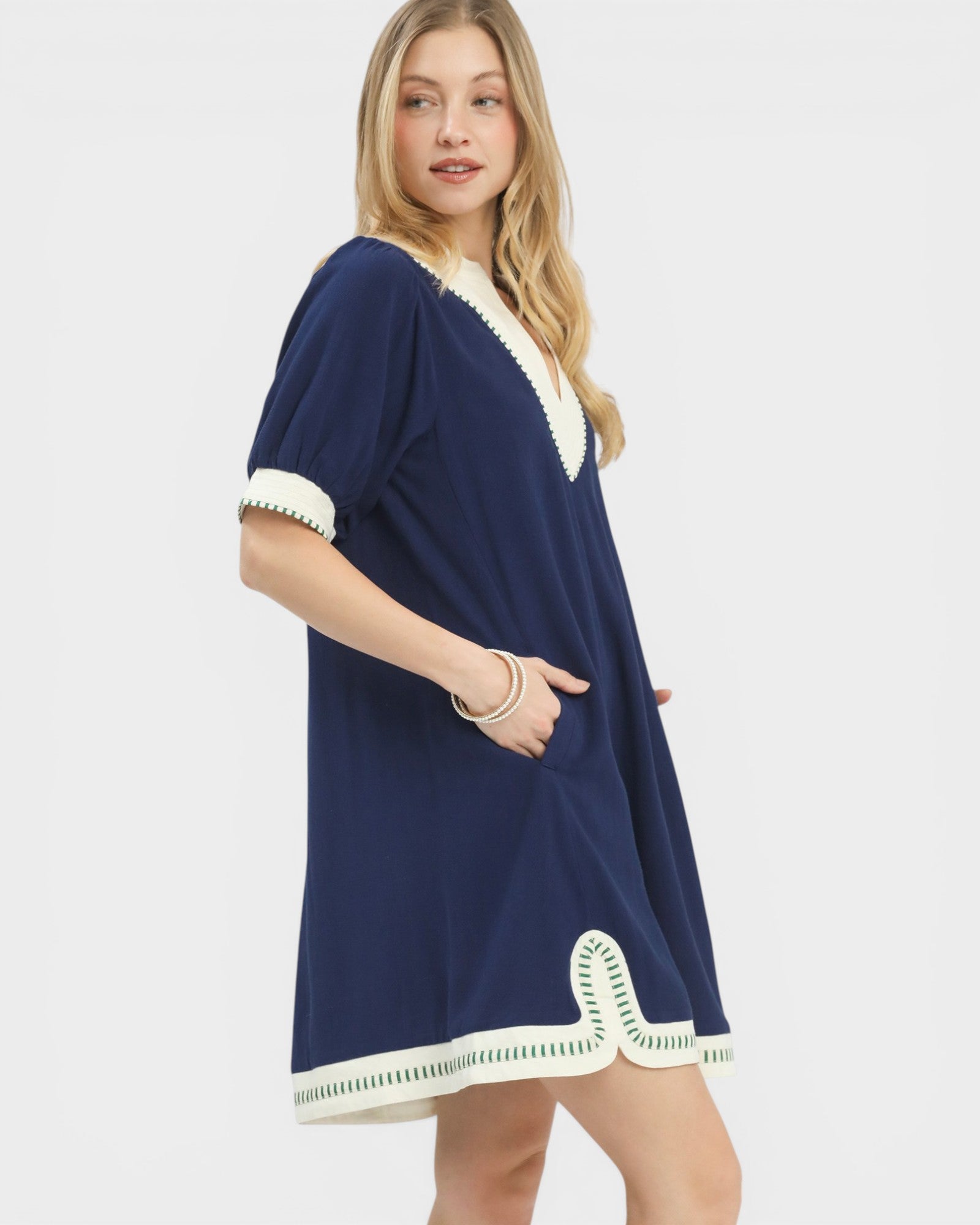 Woman wearing a navy dress with white trim on a white background