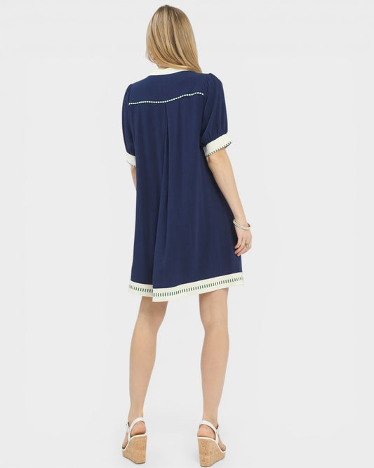 Woman wearing a navy dress with white trim on a light gray background