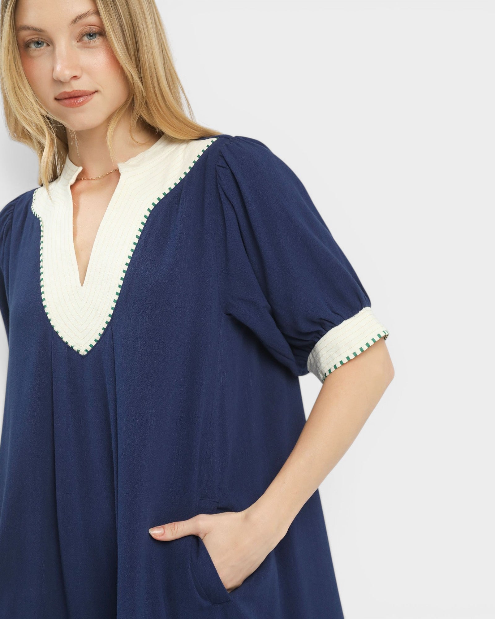 Woman wearing a navy dress with white trim on a plain background