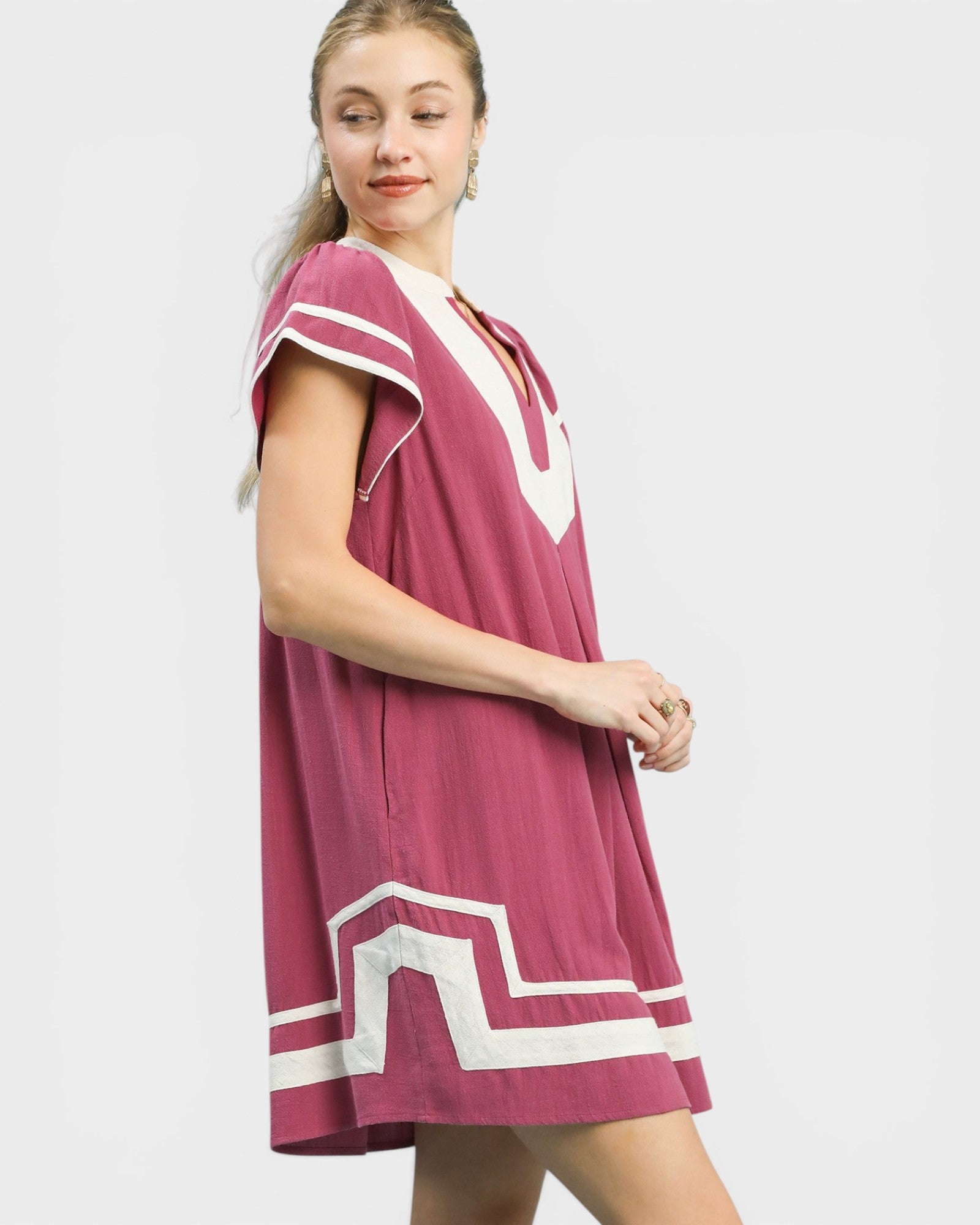 Woman wearing a pink dress with white accents on a white background