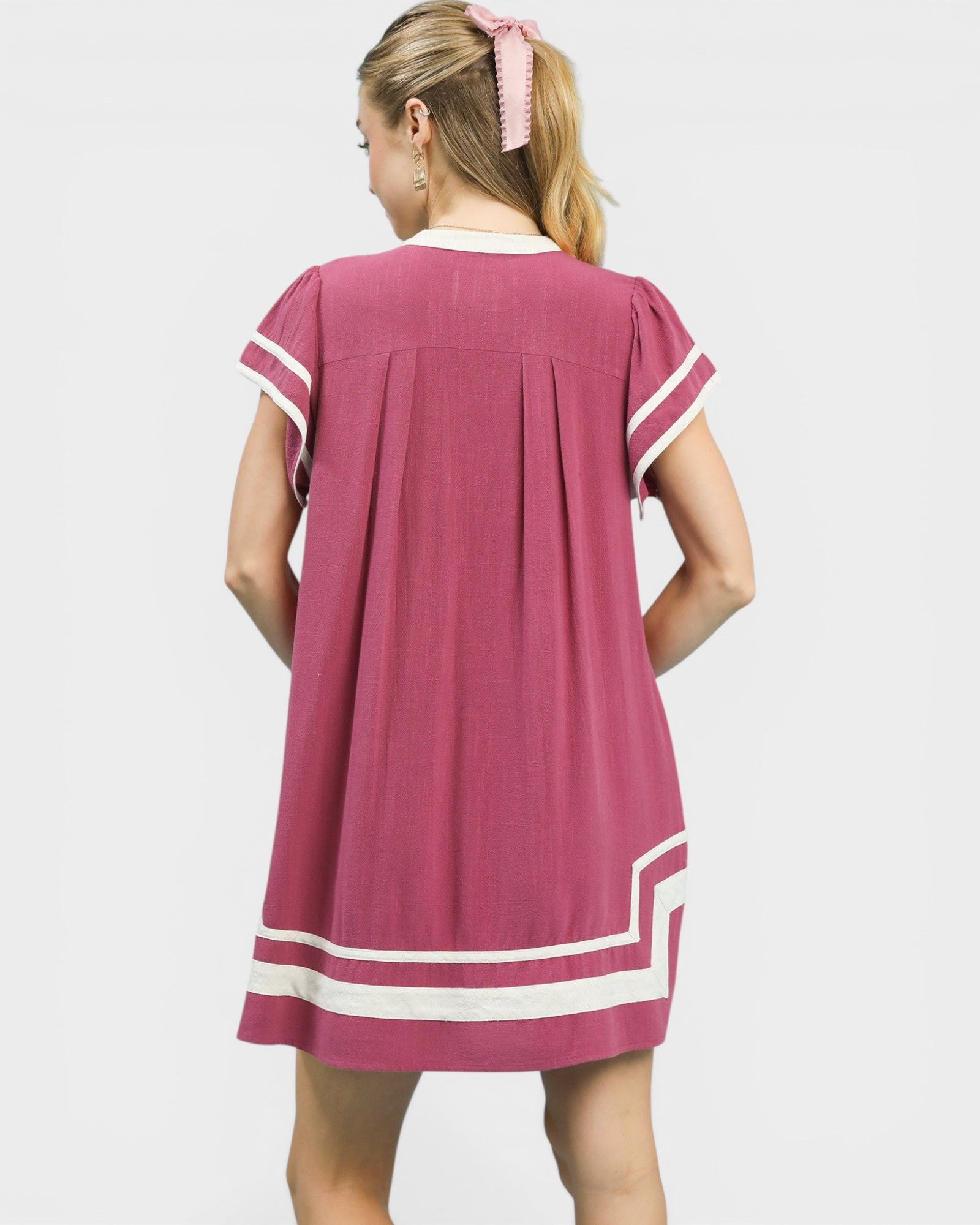 Woman wearing a pink dress with white trim on a white background