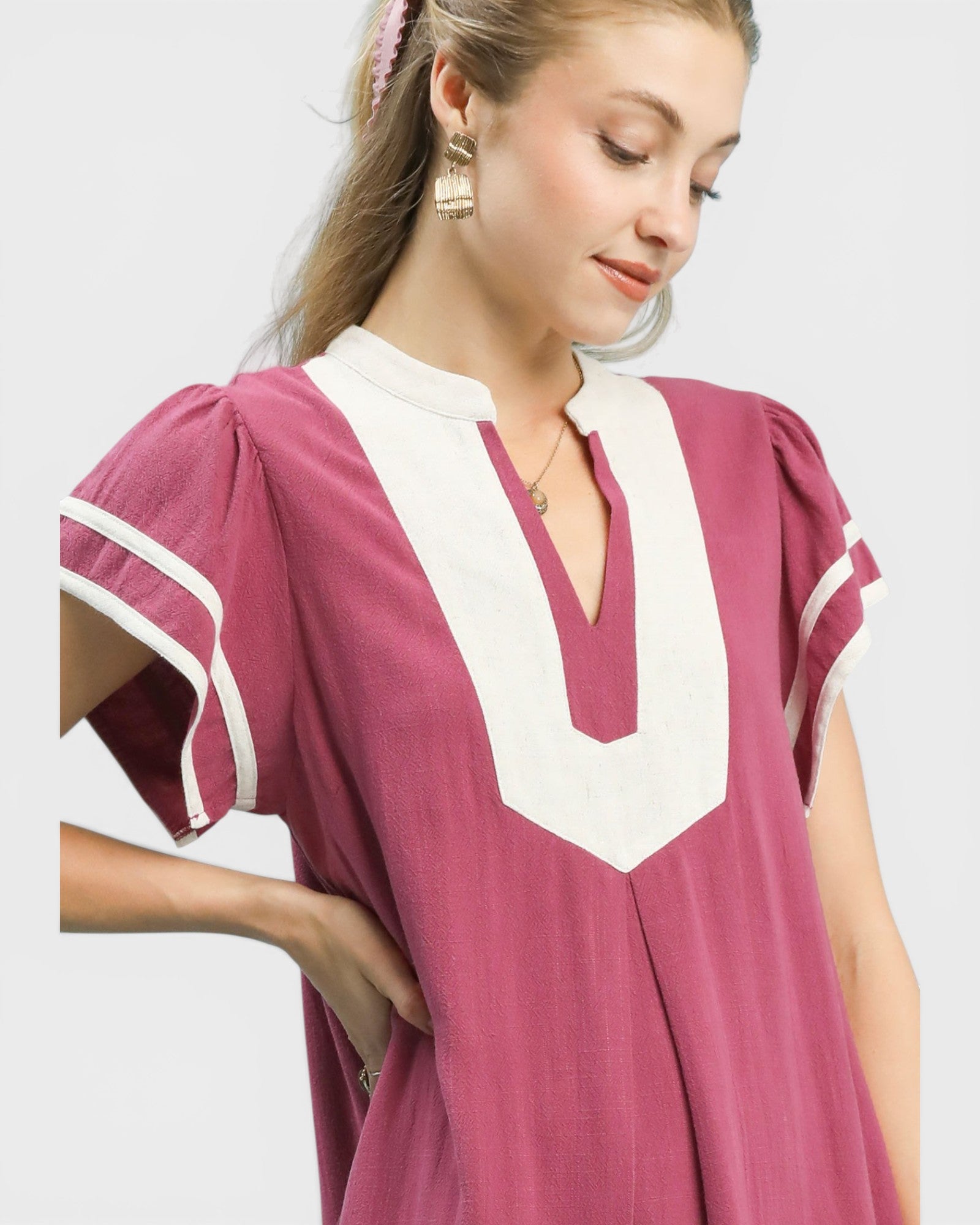 Woman wearing a pink dress with white accents on a plain background
