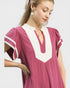 Woman wearing a pink dress with white accents on a plain background