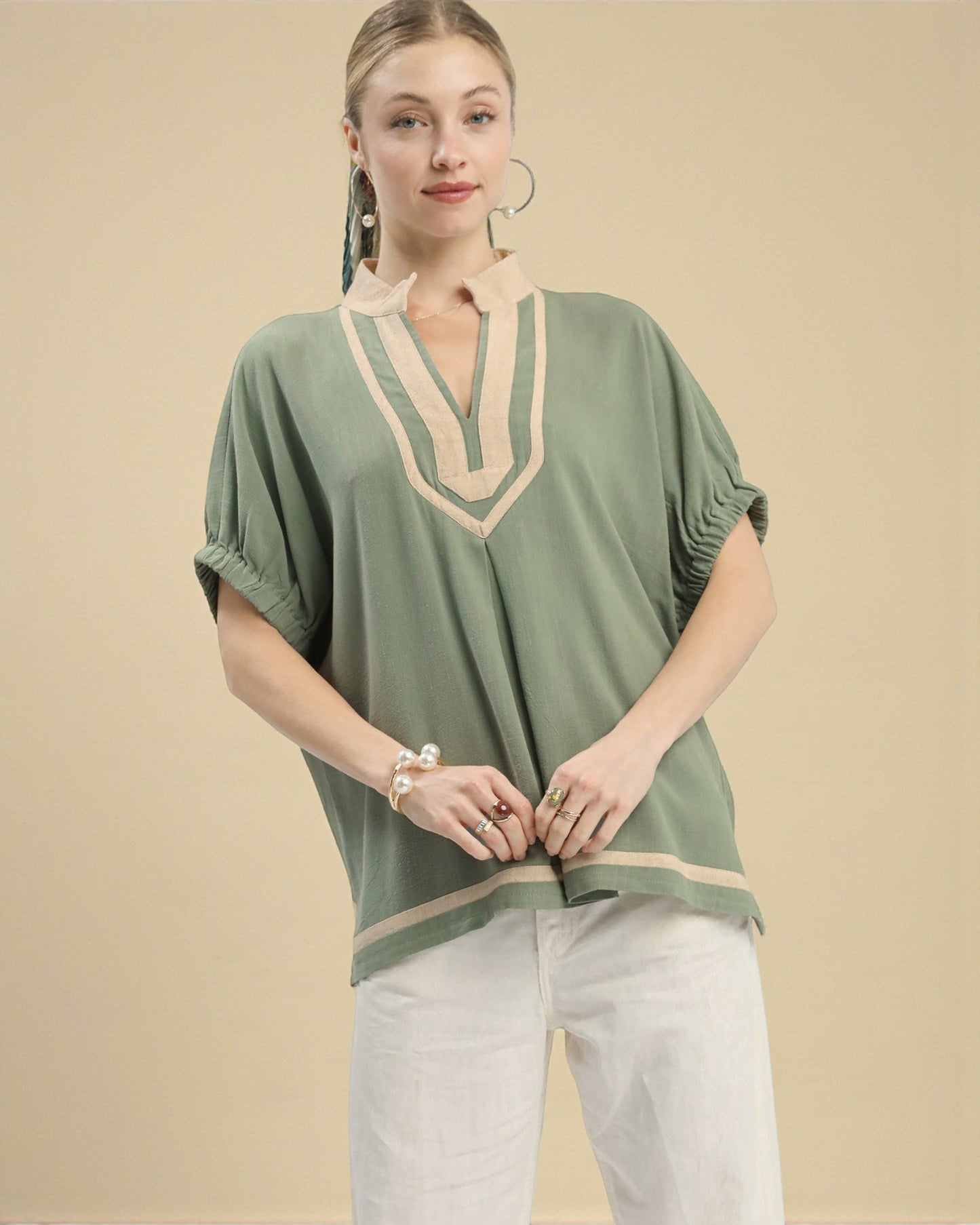 Woman wearing a green top with beige accents on a beige background