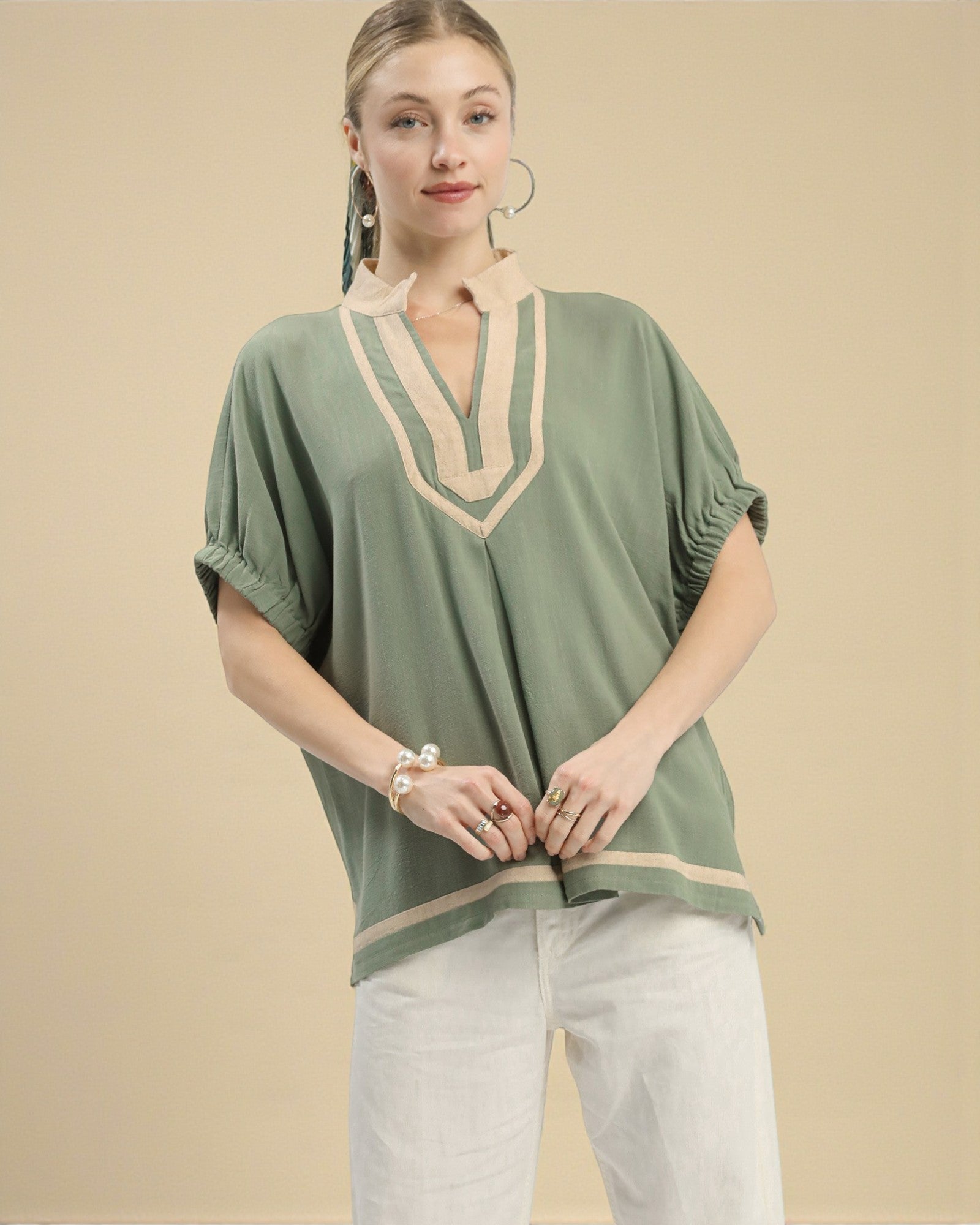 Woman wearing a green top with beige accents on a beige background