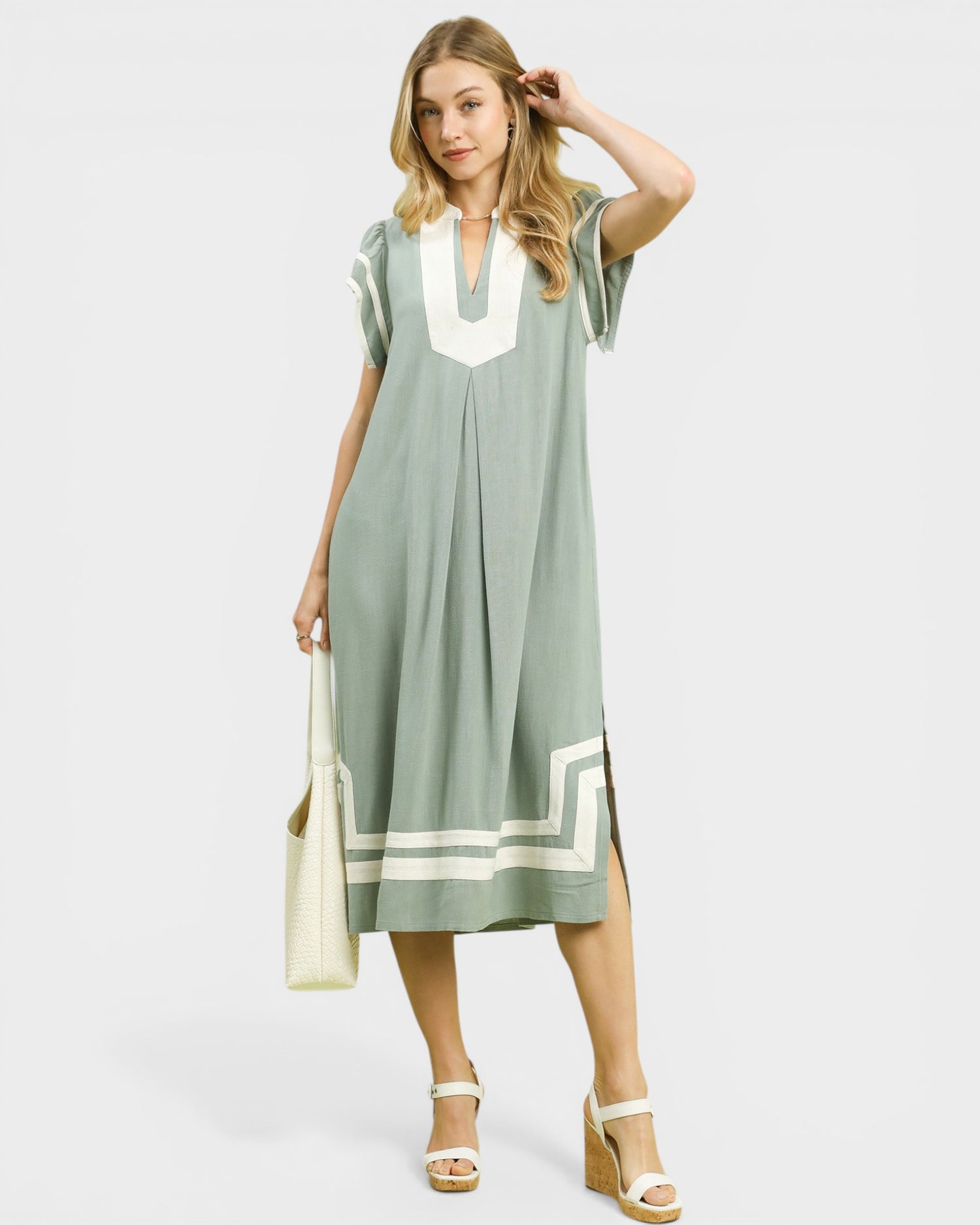 Woman wearing a green dress with white accents on a white background