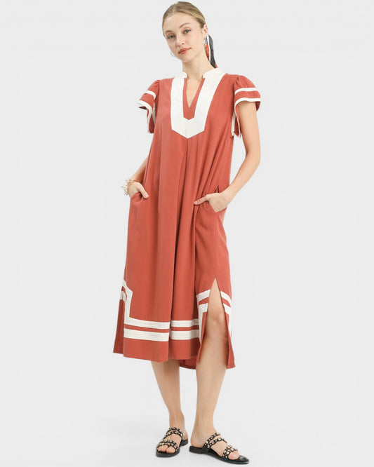 Woman wearing a rust-colored dress with white accents on a white background