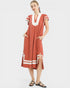 Woman wearing a rust-colored dress with white accents on a white background
