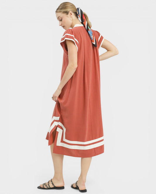 Woman wearing a rust-colored dress with white stripes on a white background