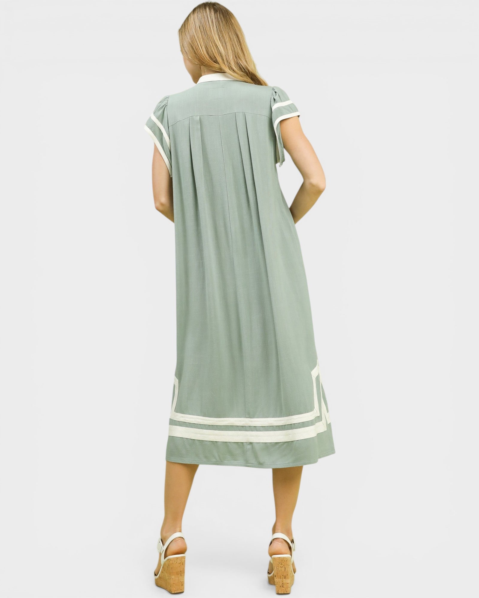 Woman wearing a green dress with white trim on a white background