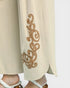Beige pants with intricate brown embroidery on a white background