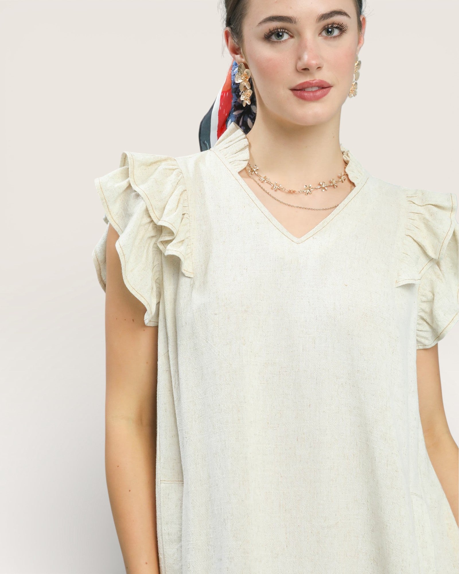 Woman wearing a white dress with ruffled sleeves against a plain background