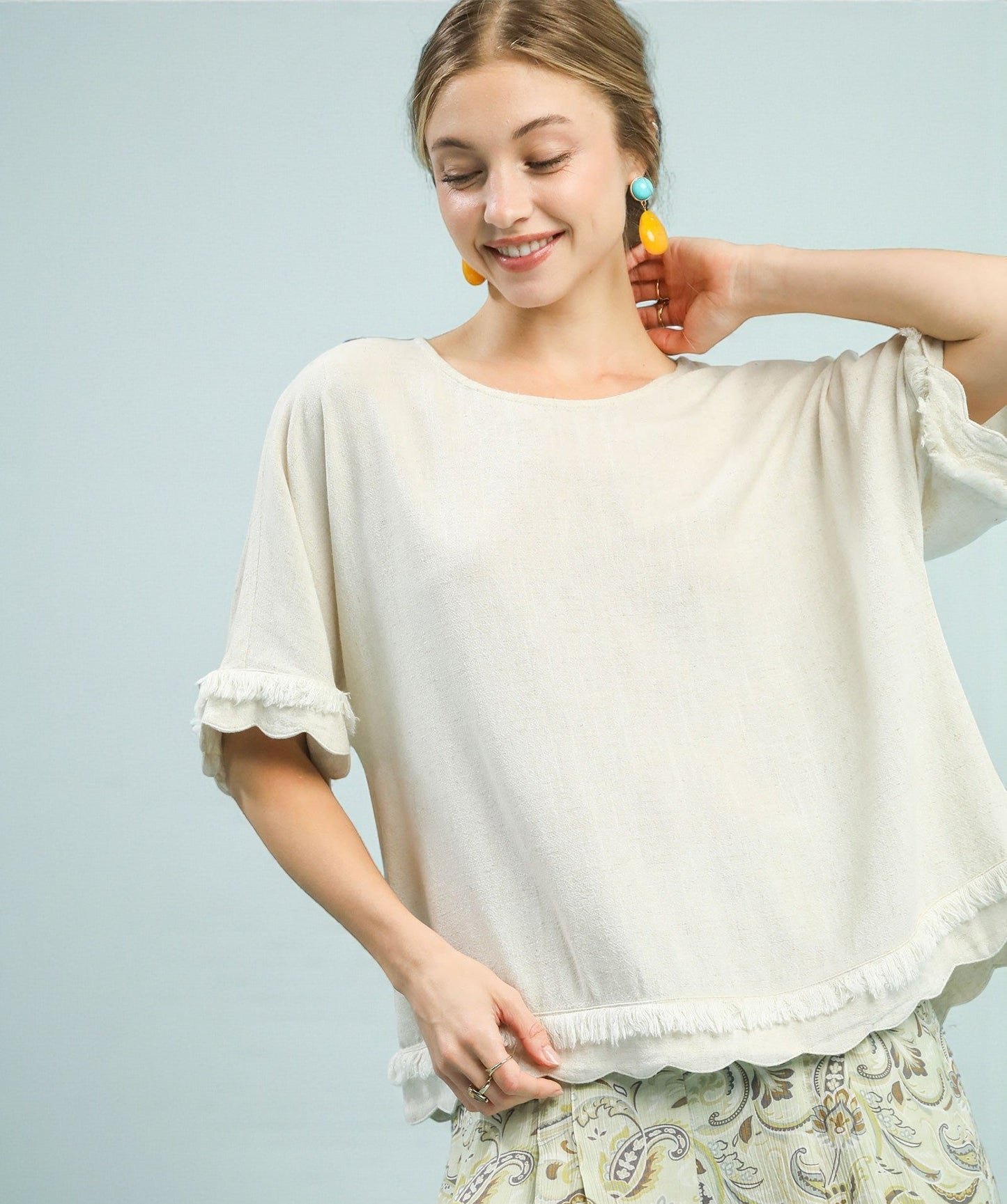 Woman wearing a white blouse with ruffled sleeves against a light blue background