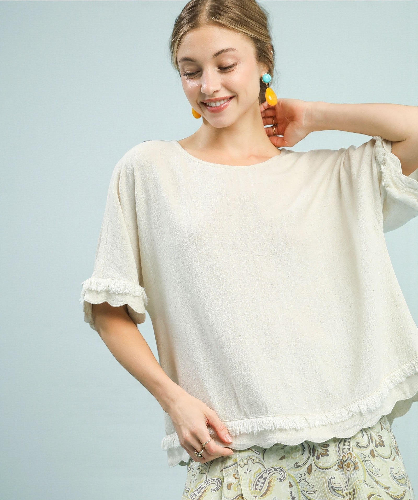Woman wearing a white blouse with ruffled sleeves against a light blue background