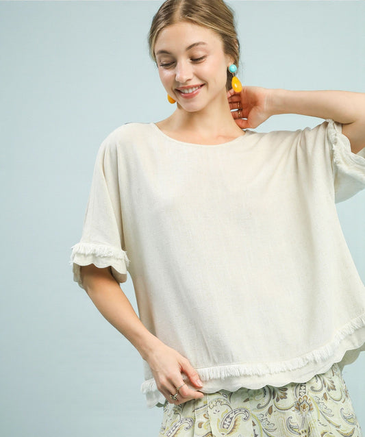 Woman wearing a white blouse with ruffled sleeves against a light blue background